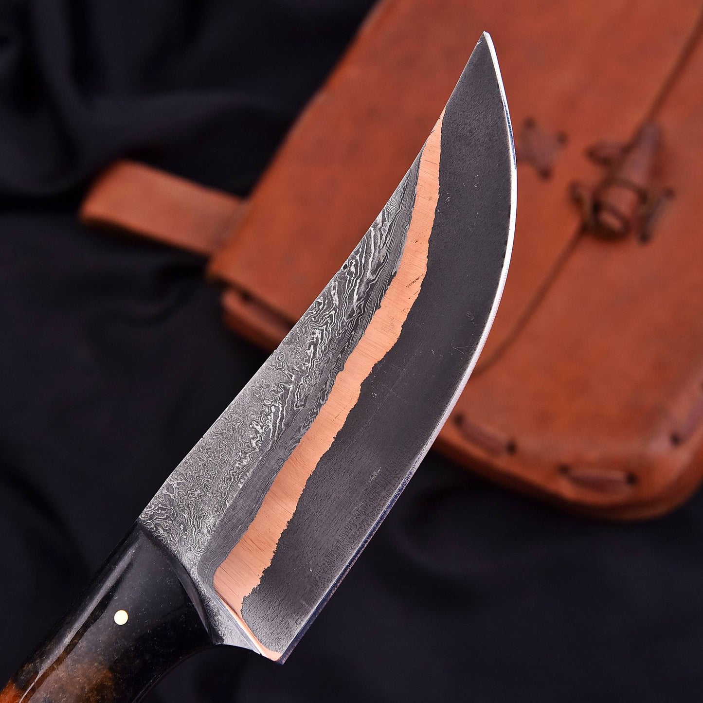 Close-up of a copper mai knife with a brown sheath on a dark background