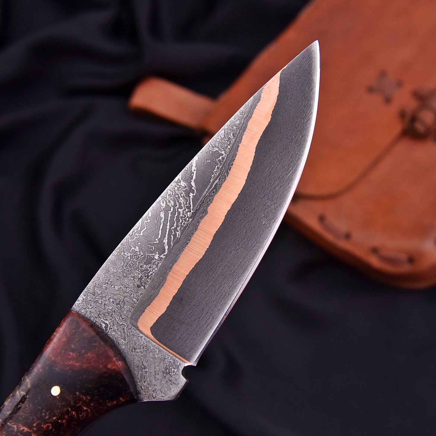 Close-up of a knife with a brown handle and blade on a dark background