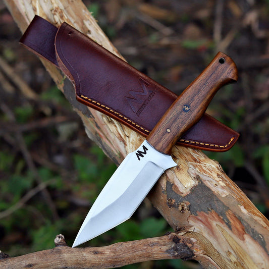 AM Frontier 9 inch fixed blade tanto knife photographed outdoors – handcrafted 12C27 Sandvik steel with rosewood handle and leather sheath.
