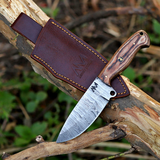 Hand-forged Damascus fixed blade knife with wood handle photographed outdoors in natural light.