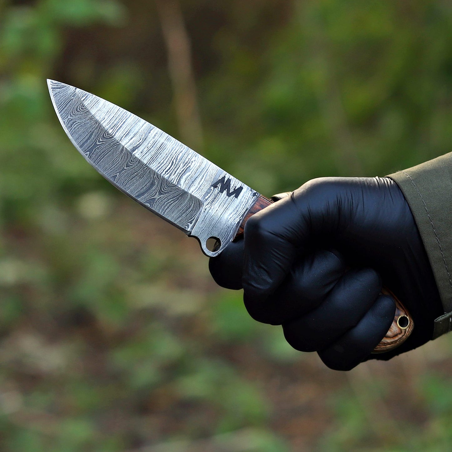 AM Vulcryst Damascus knife held in hand showing ergonomic rosewood handle and balance.
