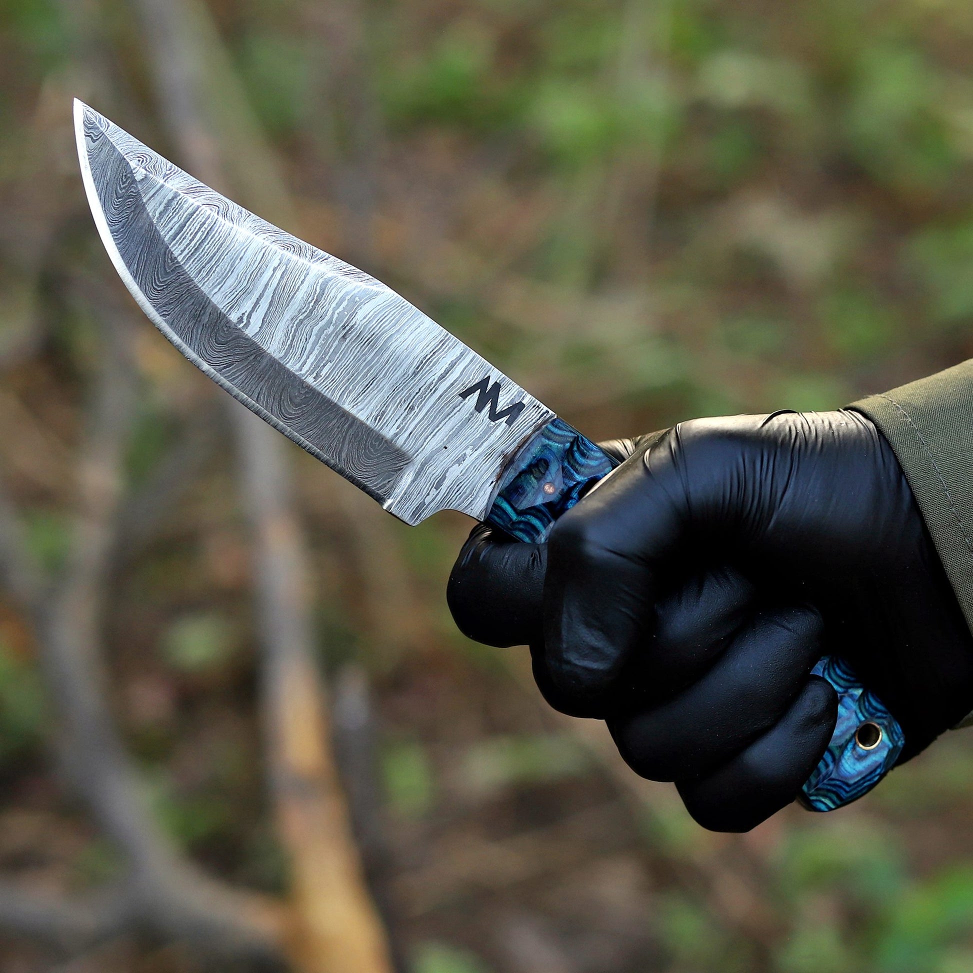 AM Helix Damascus knife held in hand showing ergonomic blue wood handle and balance